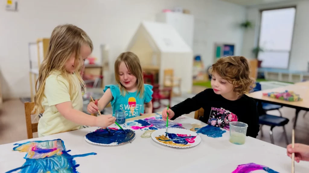 Three preschoolers painting at a table at Presbyterian Day School Napa