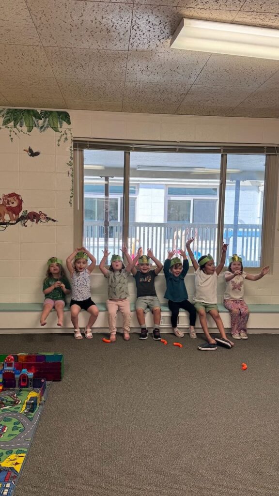 children raise their hands above their heads during an acitivty at preschool